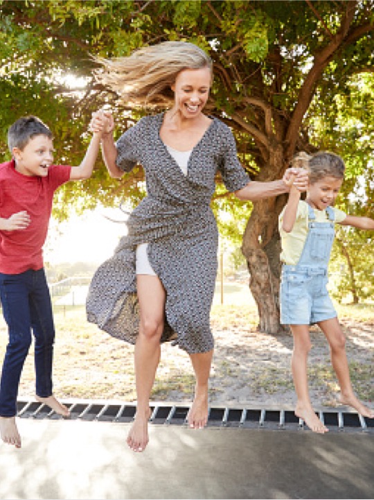 woman jumping with children on trampoline
